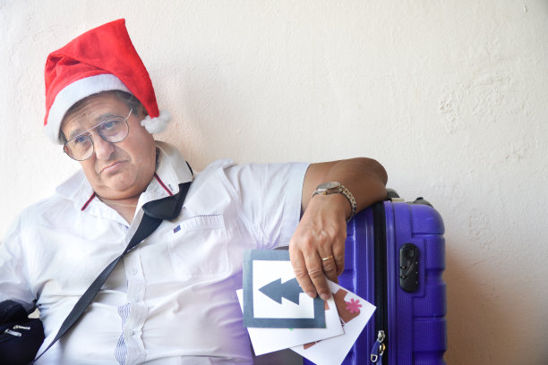 带着圣诞帽和行李的悲伤男人。返回工作岗位图片下载