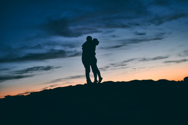 夕阳下一对情侣在大自然中亲吻的剪影图片下载