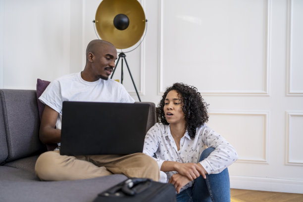 一对非洲情侣一边看着笔记本电脑一边聊天图片下载