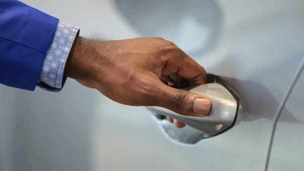 在汽车沙龙，销售人员手开汽车向顾客展示图片下载