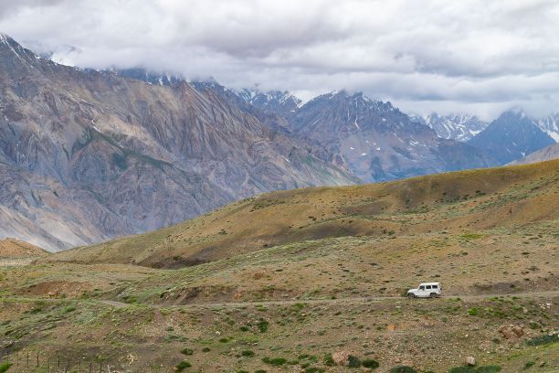 吉普车行驶在通往印度塔什港的路上，周围是群山和干草地图片下载