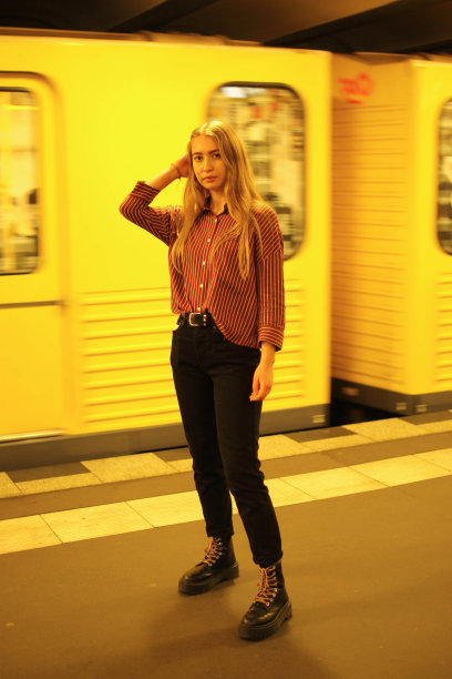 地铁里一个金发女孩穿着便装站在一辆驶过的黄色地铁旁边图片下载