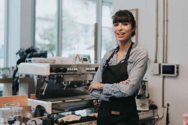 快乐的女咖啡老板站在咖啡店的柜台后面。站在咖啡馆柜台后面的女咖啡师。企业主概念。图片下载