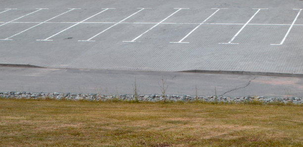 巨大的空停车场，白色的标志作为停车，草地在前景图片下载