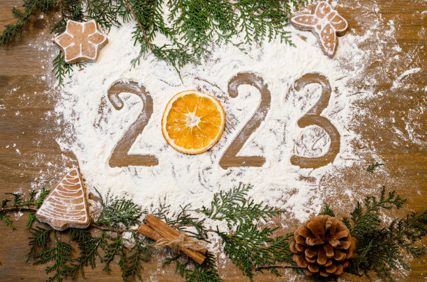 2023年新年数据文字近写铭文在木桌上的面粉背景肉桂，姜饼干橘子，云杉树枝图片下载