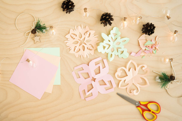 彩色的剪纸雪花，在一个木制的背景。用彩纸剪雪花。雪花冬天的背景。简单的冬季儿童工艺品想法。图片下载