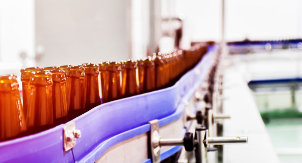 啤酒瓶在传送带上进入啤酒装瓶过程图片下载