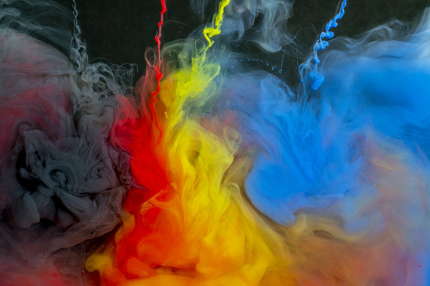 红色、黄色、蓝色和灰色的颜料从一根针流入黑色背景上的一碗水里图片下载