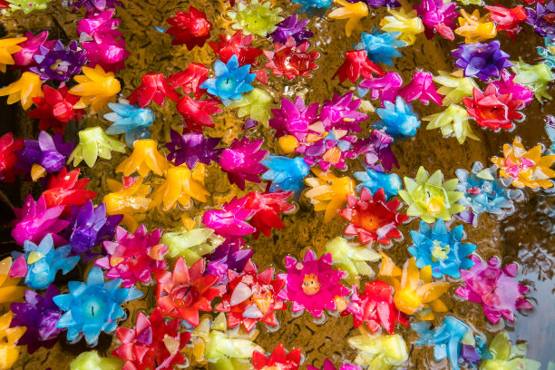 各种颜色的蜡烛漂浮在水塘表面的背景。在佛教的宗教信仰仪式中，五彩缤纷的花烛式漂浮在水面上做礼拜立功图片下载