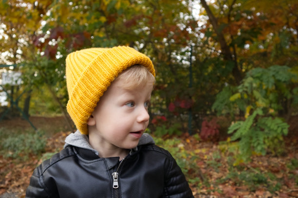 一个戴着黄色帽子的金发小男孩，背景是秋天的森林图片下载