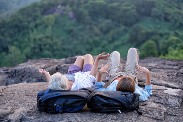 双肩包冒险徒步旅行者母女坐着，躺在山上看高高的风景图片下载