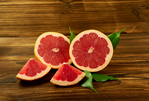 柚子的一半和切片与叶子在木制背景。美丽的照片壁纸的水果图片下载