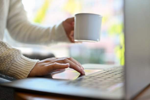 一位女性自由职业者在咖啡店远程工作，一边喝咖啡一边用笔记本电脑。图片下载