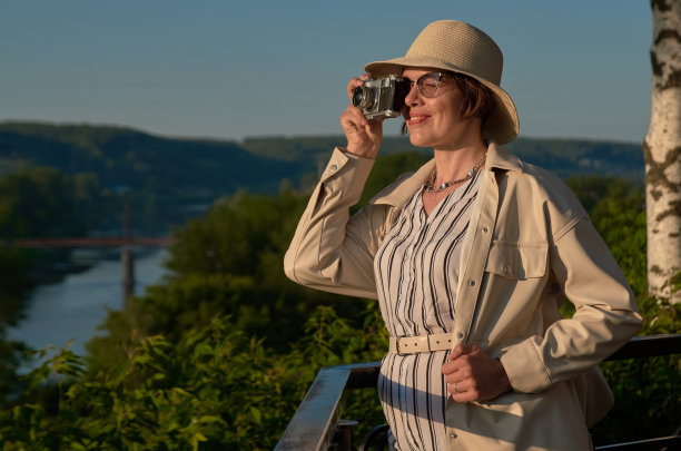 戴草帽的女游客拿着老式相机在街上拍照图片下载