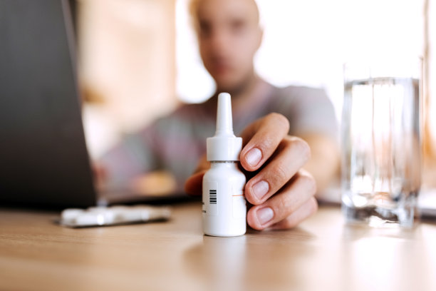 男人伸手去拿桌上的鼻喷雾剂图片下载