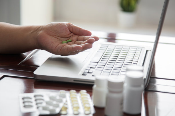 笔记本电脑和手持药片的特写图片下载