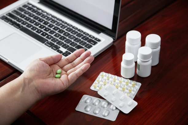 笔记本电脑和手持药片的特写图片下载