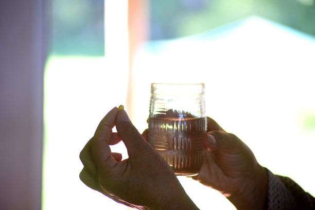 一个女人在她的房间里拿着一杯水吃药图片下载