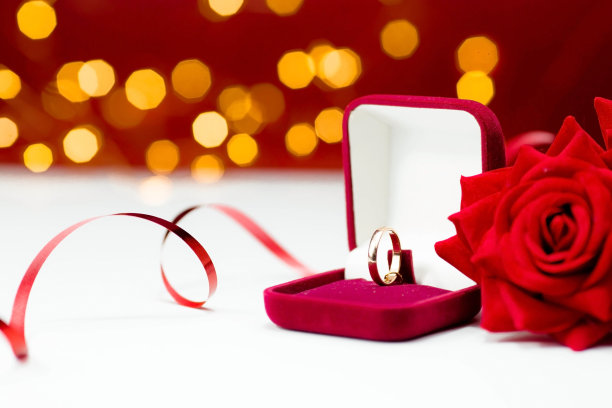 横幅。金戒指，结婚戒指在红色的盒子和，红玫瑰在白红色的背景与美丽的散焦。结婚、周年纪念、订婚或情人节的时刻愉快的一天。图片下载