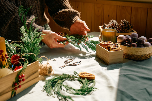 一名妇女用冷杉树枝和干橙子做圣诞安排。女性的双手创造了圣诞手工艺手工装饰。庆祝新年。冬天的假期。图片下载