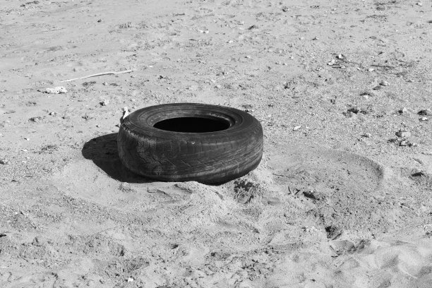 一个被遗弃在海滩上的旧轮胎。图片下载