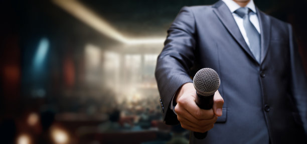 一个西装革履的男人拿出一个麦克风。图片下载