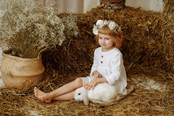 一个可爱又漂亮的小女孩和一只兔子坐在干草垛上图片下载