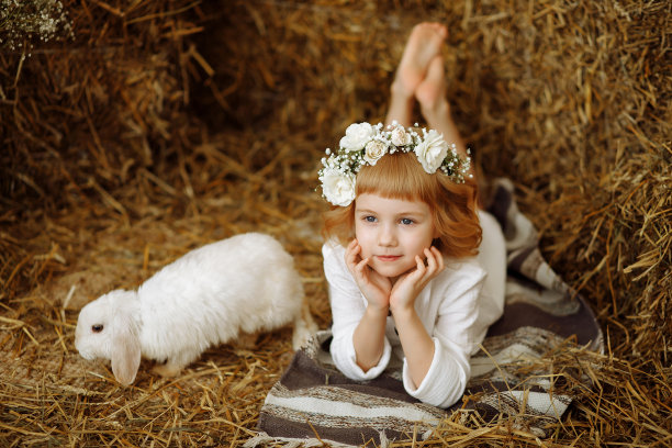 一个可爱又漂亮的小女孩和一只兔子坐在干草垛上图片下载
