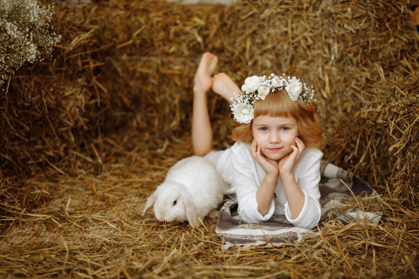 一个可爱又漂亮的小女孩和一只兔子坐在干草垛上图片下载