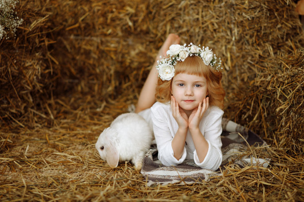 一个可爱又漂亮的小女孩和一只兔子坐在干草垛上图片下载