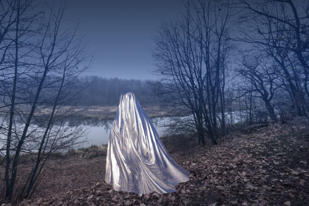 一个幽灵在雾沉沉的秋天森林里，披着一件彩虹色的斗篷。幻想，神秘主义，万圣节。图片下载