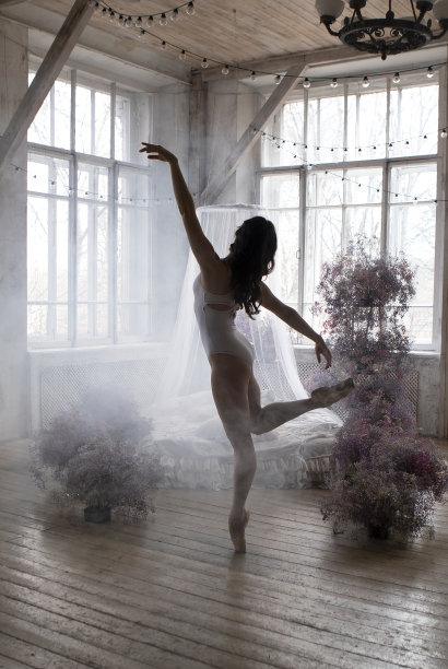 一位身穿白色体操紧身衣的职业芭蕾舞演员正在蓝色墙壁的房间里跳舞图片下载