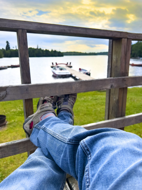 第一人称视角:在远处有湖和船坞的甲板上放松。一天结束时，一只面目全非的雄性正在休息图片下载