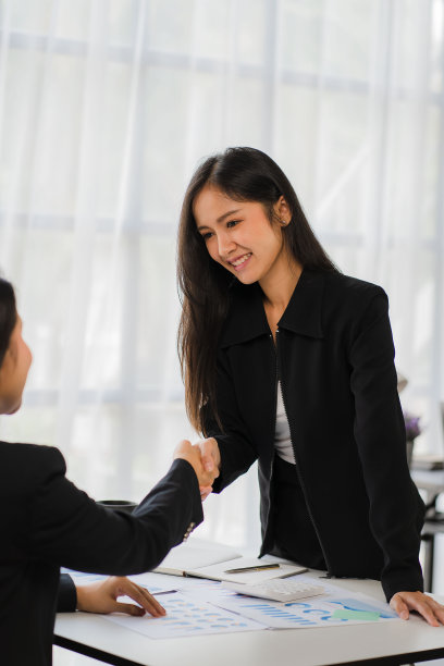 两位女商人在桌旁握手达成交易或合作图片下载
