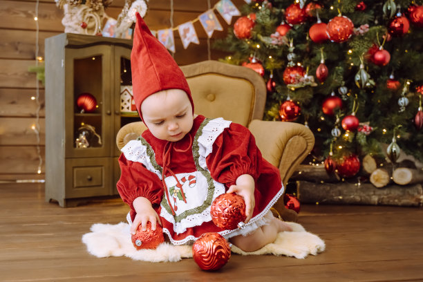 可爱的孩子带着圣诞树。快乐的孩子坐在圣诞树旁图片下载