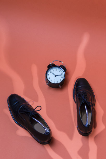 上视图对正式的男性时尚黑色抛光牛津皮革花边鞋放置在一起手表时钟在橙色南瓜背景图片下载