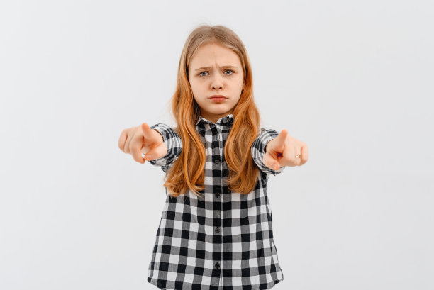 肖像愤怒的少女穿着休闲衬衫点食指相机，看起来关切，站在白色的背景图片下载