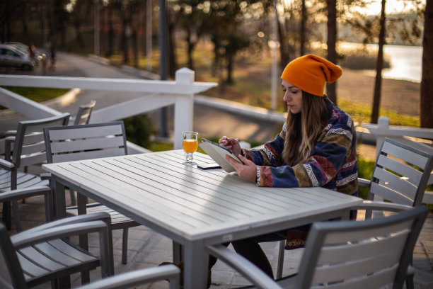年轻漂亮的女人正坐在阳台上摆弄她的平板电脑。图片下载