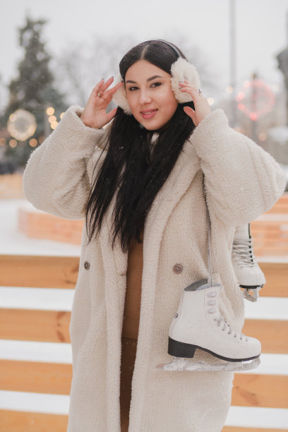 美丽的白人妇女在温暖舒适的衣服滑冰冰场，因为下雪。图片下载