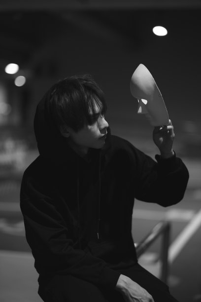 万圣节肖像的一个年轻男子在黑色的衣服拿着一个白色的面具在他的手中，并看着面具图片下载