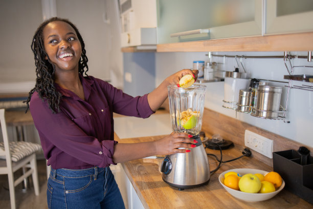 年轻女子在家里榨汁图片下载