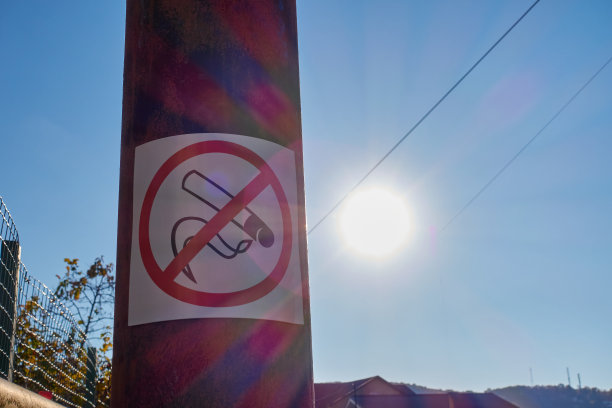 杆子上禁止吸烟的标志。蓝天上灿烂的日落。图片下载