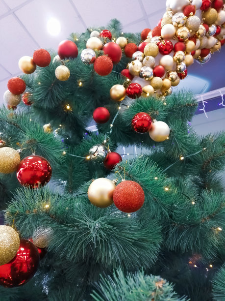 红色和黄色的圣诞树玩具挂在圣诞树上。垂直照片装饰圣诞树为圣诞节和新年。圣诞树上的圣诞球组成。图片下载