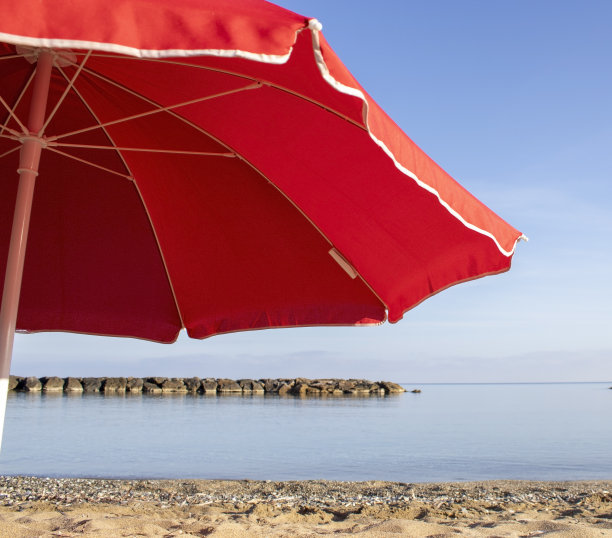伞滩背景。蓝色海洋背景下的红色海滩伞。海滩的风景。海洋背景。多彩的夏日设计。准备明信片和横幅图片下载