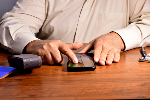 一名男子用拇指在手机上翻看。图片下载