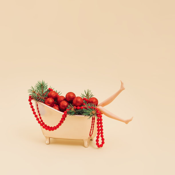 塑料娃娃在复古的浴缸里，有圣诞装饰，冷杉树枝和红色珍珠项链。休闲、水疗、娱乐和寒假的概念。图片下载