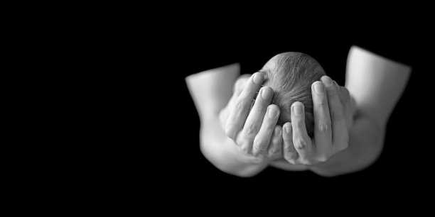 父亲捧着刚出生的儿子的头。手里抱着的婴儿望着爸爸。慈爱的父亲手抱着可爱的熟睡的新生婴儿图片下载