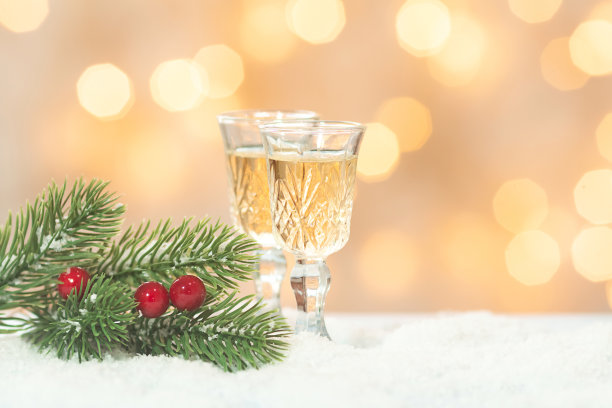 酒杯香槟和绿色的杉树树枝模糊明亮的背景与散景灯。副本的空间。新年节日晚会的概念。图片下载