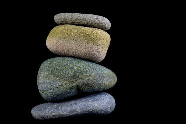 一堆孤立在黑色背景上的鹅卵石图片下载