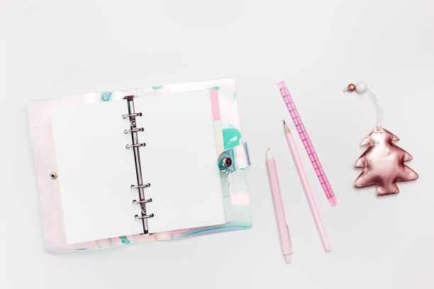 新年计划的概念，女孩的工作空间，打开空白的剪贴簿或日记，钢笔，铅笔，粉色金属色圣诞树和闪亮的星星在白色。假期学校文具趋势平平图片下载